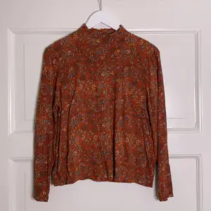 Rostbrun tröja med blommor från Indiska. Dragkedja i ryggen. Liten krage, nästan som en polotröja. Använd ca 5 ggr. 