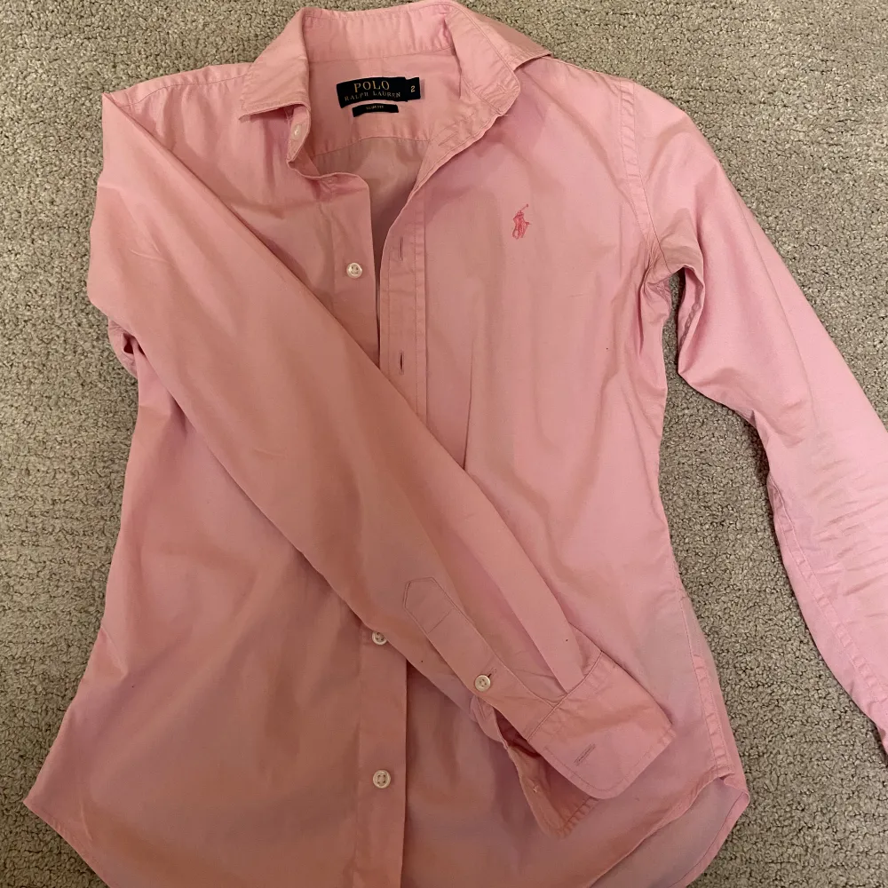 Jättesnygg Ralph Lauren slim fit skjorta i rosa färg. Säljer då den är aningen för liten för mig. Har vanligtvis storlek S. Använd nån gång och är i jätte fint skick. Köparen står för frakten, kan även mötas upp i Stockholm❤️. Skjortor.