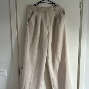 Beige Kostymbyxor  - Ett par beige kostymbyxor från bikbok i storlek 38 !bra stick på dem eftersom jag knappt har använt dem. Orginalpris 500