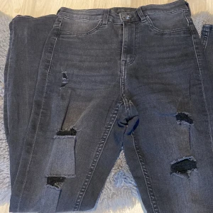 Jeans  - Jeans med ”slitage”. Svartgråa slimmade i stretchbar material. Oanvända. 