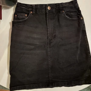 Jeanskjol - Jeanskjol i en urtvättad svart färg   Sitter tajt och säljer då den är för liten för mig. Storlek 36