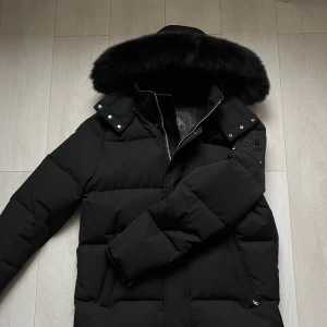 Moose knuckles - Moose knuckle jacka med svart päls, modellen heter CLOUD 3q. Jackan är i nyskick, köptes december 2021 men använts ett fåtal gånger. Jackan är storlek XL men sitter mer som L då moose knuckle tenderar att vara små i storlek. KVITTO FINNS