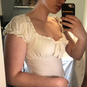 Vit milkmaid-topp - Helt oanvänd men lappen är borttagen. Toppen är i mjuk bomull. Står storlek L på lappen men passar som en M.   Kan bäras så den har en fyrkantig urringning eller som off-shoulder