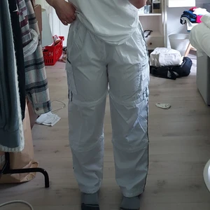 Sportbyxor  - Supersköna sportbyxor i luftigt material med svarta stripes längst benen samt sidorfickor på benen. Man kan korta ned byxorna i 2 olika längder till short, superskön detalj särskillt på sommaren! Säljes för 300 kr + frakt som köparen står för själv 💕