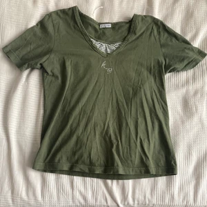 T-shirt med y2k känsla - Fin mjuk tröja med gulligt randigt tyg på bröstet. Tycker den har lite nostalgisk 00-tals känsla med detaljerna och det glittriga initialerna! Super härlig militär färg 