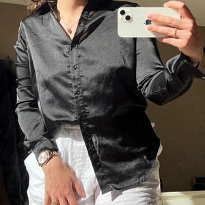 Glansig Svart skjorta  - Jättefin svart skjorta som är i ett glansigt material, använd fåtal gånger då den är lite stor enligt mig i överkroppen. Jättefin i superbra skick😊 köparen står för frakt😊