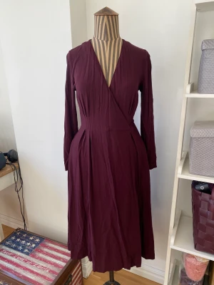 Vinröd klänning med fickor - Jättefin vinröd klänning från Uniqlo, specialkollektion. Lite längre modell med fickor.  Lite skrynklig efter att ha legat nerpackad men i övrigt i jättefint skick. Storlek XS men passar även S om man inte har så styr byst.