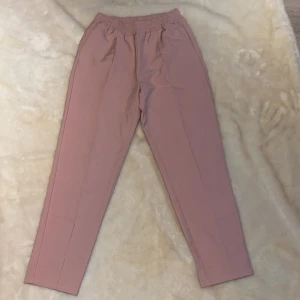 Kostymbyxor  - Extremt sköna kostymbyxor i en gammalrosa färg med resår i midjan! Sitter väldigt fint på kroppen! Aldrig använda!