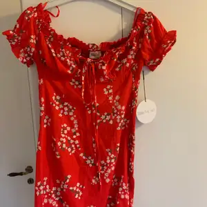 Jättefin röd klänning med blommor, fina detaljer. Aldrig använd.
