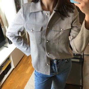 Skjorta/overshirt nakd - Fin lite tjockare grå-beige skjorta med pärlknappar från NAKD. Går även att använda som overshirt. Använder aldrig så bättre någon annan får användning av den☺️. Väldigt skönt material. Storlek 40. Axelvaddering.