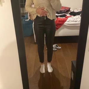 Läderbyxor  - Svarta läderbyxor med en dragkedja på vänster höft. Stretchigt material och snygga sömmar på framsidan av benen. 