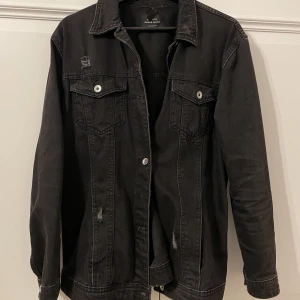 Svart jeansjacka  - Svart jeansjacka med slitningar. Mycket bra skick. Inga defekter eller fläckar - ser ut som ny.  