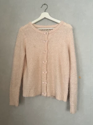 Stickad tröja - Jättefin stickad fluff tröja i en rosa färg med rosetter! Super söt och köpt second hand! Sparsamt använd! Skriv privat för bild på🫶🏼💋