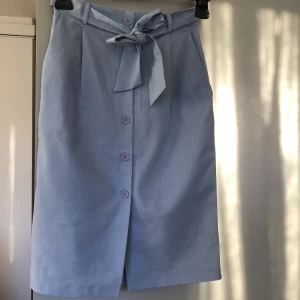 Oanvänd midikjol med knyt - Oanvänd kjol med knappar och knytband. Jättefin ljusblå färg. Strl s