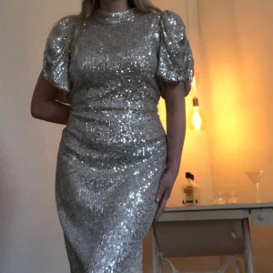 Lång paljettklänning  - Lång, fin klänning med paljetter på. Använd en gång. Klänningen har lent tyg på insidan, vilket gör att den ej är obekväm att ha på sig. Ärmarna är vida och skaver inte. Dragkedja på ryggen och skön passform.  Storlek: 40