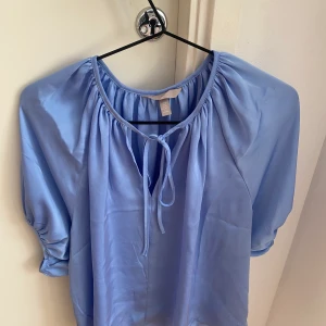 Blå blus  - En blå blus från HM. Den är jätte fin säljer den för den är för stor för mig och tror den skulle passa någon anna bättre. Den är i silken  material. Den är ganska stor i storlek, den är mer S/M än XS tycker jag. Den är aldrig använd. Kan sicka mer bilder privat. 