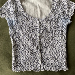 Blommig topp Brandy Melville  - Vit och mörkblå blommig topp från Brandy Melville. Lite missfärgad vid armarna men knappt märkbart 