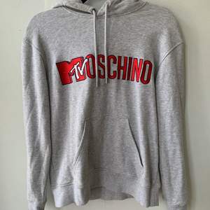 Grå hoodie från Moschino x H&M kollektion.  Använd 2 ggr så den är i mycket bra skick och nästa som ny. Storlek: S 