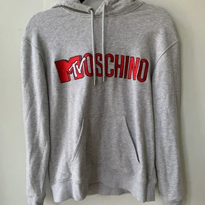 Moschino x H&M Hoodie - Grå hoodie från Moschino x H&M kollektion.  Använd 2 ggr så den är i mycket bra skick och nästa som ny. Storlek: S 