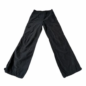 Mörkgrå Cargo Byxor - Säljer dessa coola byxor med spännen nere vid fötterna! Storlek 34, 73cm midja och 82cm innerbenslängd, och passar då tyvärr inte mig (som är storlek 38)❤️ Cool brodering nere på ena vaden syns på bild 3💕