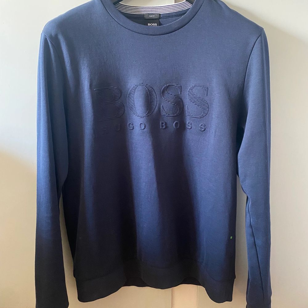 Hugo Boss blå sweatshirt, plagget är i slim fit men sitter som en klassisk sweatshirt. Produkten är använd ett fåtal gånger, men är i väldigt bra skick nästan nyskick.  Det finns inga skador eller defekter. . Tröjor & Koftor.