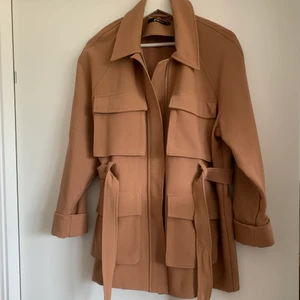 Brun jacka/kappa - Brun tunnare jacka/kappa från GinaTricot. Riktigt bra skick förutom mindre slitage på ena ärmen längst ned. (Se bild 4). Storlek 38, riktigt bekväm då den är lite stretchig.  Finns i Kallebäck, Göteborg men kan även skickas mot fraktkostnad.