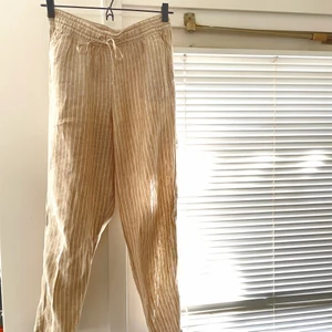 Randiga linnebyxor - Svala linnebyxor i beige färg med vita ränder och knyt i midjan, passar både avslappnat till stranden eller mer uppstyrt med en fin topp. Är ganska oversize på mig och faller på höfterna istället för att sitta i midjan som jag tror är tanken, jag är 166cm lång & bär normalt storlek 32/XXS. 