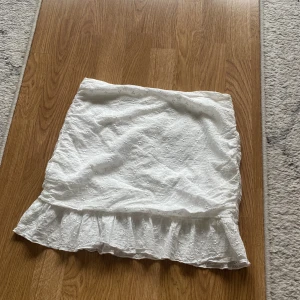 Vit Kjol från shein  - En vit kjol volang med kant nertill en kjol med brodyr av blommor i storlek M från shein dragkedja vid rumpan