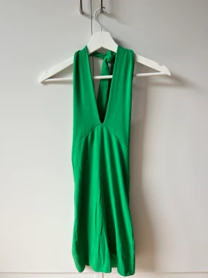 Grön klänning - En grön klänning man knyter runt halsen, från Zara i stolek M. Använd 1 gång, i mycket bra skick!
