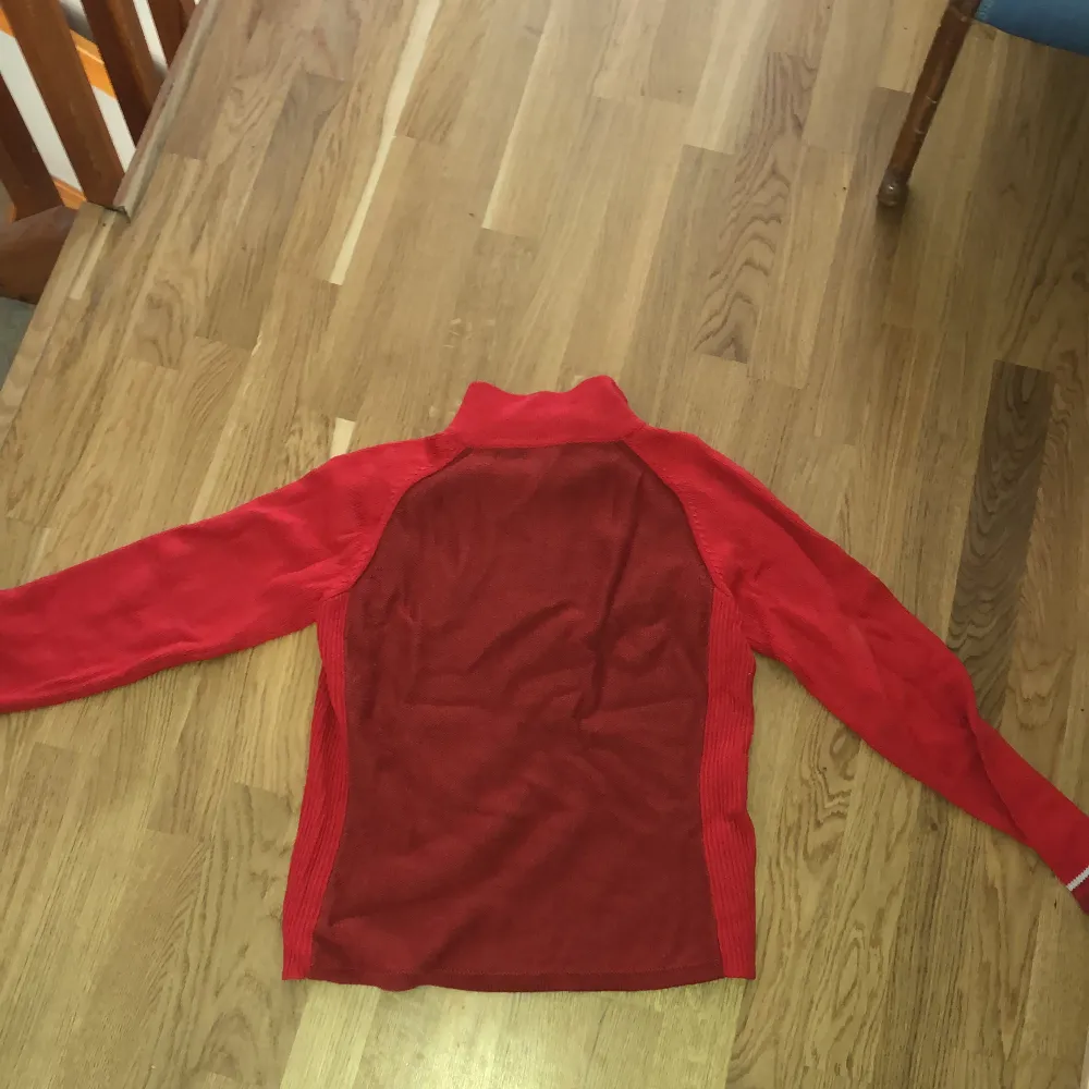 Röd tröja från The North Face med dragkedja i halsen. 50% ull 50% akryl. Står dam L på lappen men sitter kanske mer som en M.. Stickat.