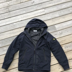 Stone island junior jacka 170  - Stone island jacka som är köpt på NK i gbg runt 2019/20. Skick 8/10. Som ny men en söm har släppt vid armhålan så ett litet hål. Storlek 170 för junior. Har ej kvitto