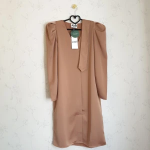 Lyxig brun satin klänning - 🥐FÖRST TILL KVARN!🥐 Elegant valnöts brun klänning i satin med puffärmar. Namn: "Cady dress walnut". Från skandinaviska märket Just Female, helt ny, lappar kvar, endast testad. Hade köpt den i förväg till en inplanerad till en fest men den var lite stor på mig när dagen kom. Nypris:1349 kr. Passform bilden 4, är tagen från hemsidan då jag föredrar att ej lägga ut bilder på mig själv.😚