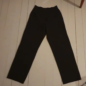 Kostymbyxa - Mörkgrå kostymbyxa med smalare midja och vidare byxben.