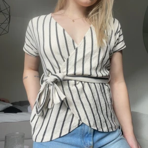 Randig blus - Fin omlottblus med knytning, använd men i fint skick. Beige/svart 