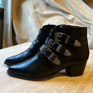 Svarta ankelboots - Ankelboots i svart skinn inköpta på Nilson. Dragkedja på insidan med 3 spännen som går över. Använda ca 10 ggr och behöver inte sulas om än på länge. 
