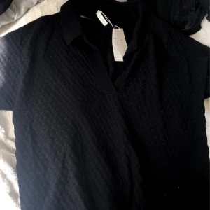 Svart t-shirt - Sjukt snygg t-shirt ish skjort liknande tröja, den är jätte skön i materialet och är helt ny, tröjan är i storlek M men passar även S beroende på hur man vill att den ska sitta, funkar till både tjej och kille. Köpt för 500kr