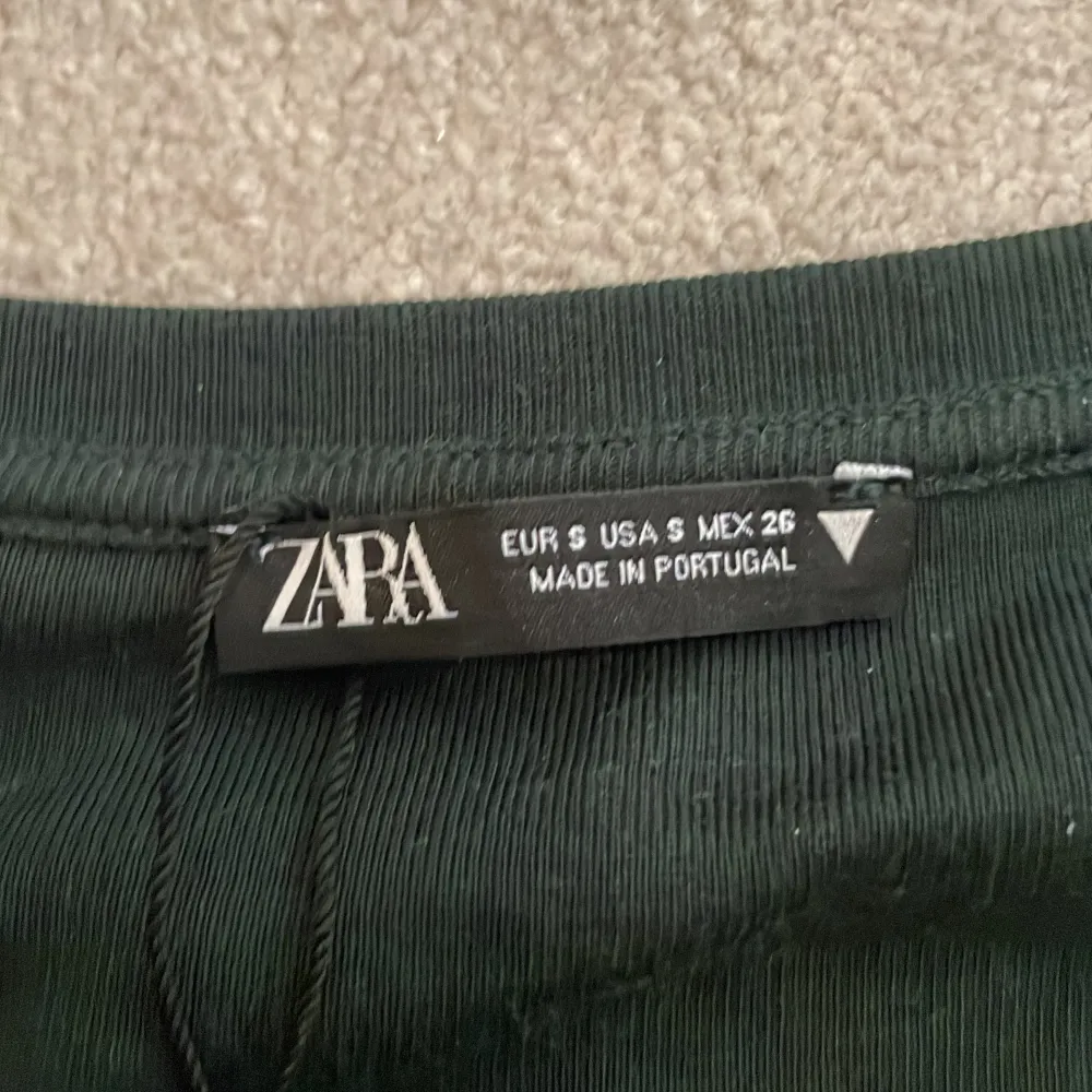 Säljer denna oanvända mörkgröna zara tshirt! Den är kort i modellen och har en cool uringning.💋 Aldrig använd!. T-shirts.