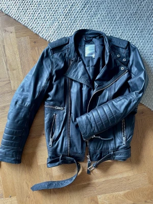 Skinnjacka J Lindeberg - Svart skinnjacka från J Lindeberg storlek S. Bikermodell Tyrone i superfint skinn. Extremt lite använt = nyskick. Nypris ca 5000 kr. 