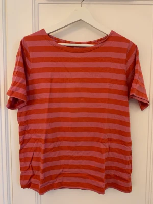 Randig t-shirt, Gudrun Sjödén  - Röd- och rosarandig t-shirt från Gudrun Sjödén. Inköpt sommar 2022. Fint skick, inget att anmärka på förutom lite smånoppror i armhålorna. 