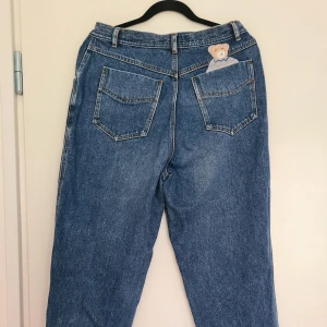 Unika momjeans - Superfina mom-jeans i hög kvalité! Vintage 80-tals jeans med unik teddybjörns-patch fram och bak. Köpta second hand. Inga lösa trådar eller tecken på användning. Strl 16, men något små i storleken, ingen stretch.