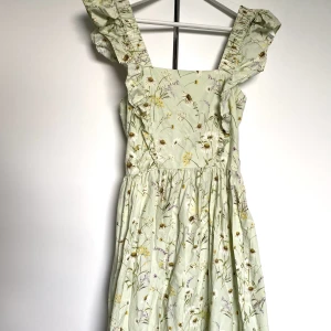 Sommarklänning - Sommarklänning med blommigt mönster från H&M som bara fått hänga i garderoben. Aldrig använd och därför i nyskick .  