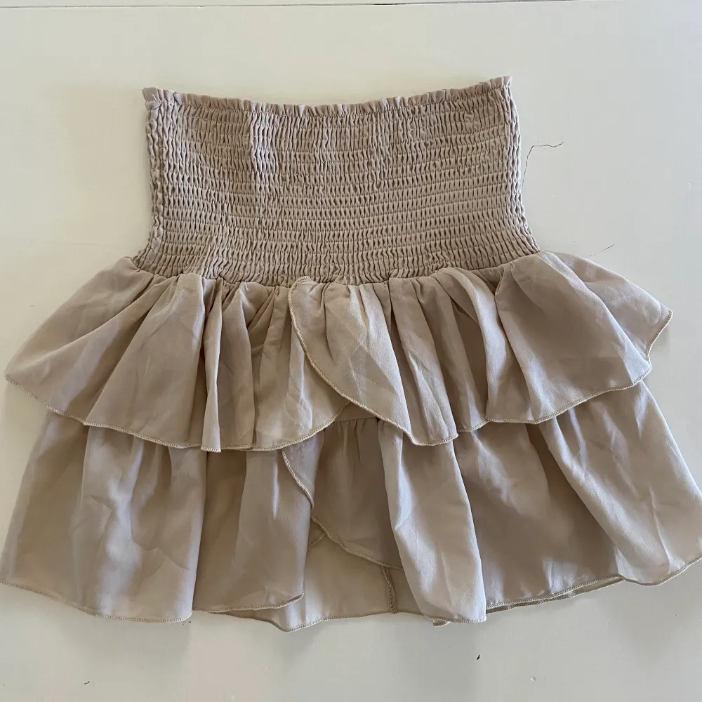 Säljer denna beiga super söta kjolen pga för liten. En jätte fin kjol som är perfelt till sommaren! . Kjolar.