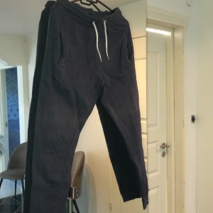 Mjukisbyxor  - Marinblå mjukisbyxor i tunt material. Fickor framtill samt vitt band runt midjan. 