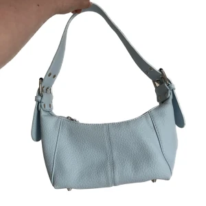 Blå hand-/axelremsväska - Ljusblå liten hand-/axelremsväska med spänne på båda sidorna från asos. Går att göra axelbandet lite kortare och lite längre. Lätt och smidig att ta med sig men samtidigt får plats med en del grejer i den😇