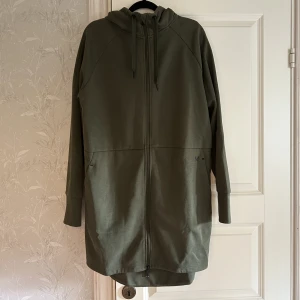 Lång tjocktröja  - En knälång tjocktröja med huva och dubbla dragkedjor. Använd en gång så den är som i nyskick. 