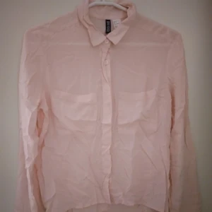 Ljusrosa luftig / sval blus med knappar fram och ryggen. Strlk: 34. Viskos. Felfri. - Ljusrosa luftig / sval blus med knappar fram och ryggen, 2 fickor. Strlk: 34. Material: Sval & bekväm Viskos.  Har knappar fram & även bak i ryggen. Ledig/lös passform. Felfri. Endast något skrynklig vid fotografering men blir fin igen efter strykning.