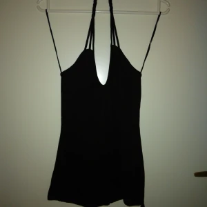 Svart oanvänd topp / linne. Flätat band i nacken, knyt nedtill. Strlk: XS-SMALL. Bomull  viskos. Felfri. - Svart oanvänd topp / linne. Flätat band i nacken, knyt nedtill. Strlk: XS-SMALL. Bomull  viskos. Felfri.