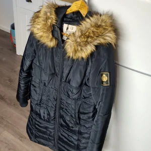 Vinterjacka - Vinterjacka från chiara forthi(bubbleroom) Storlek 42,mörkblå,smal modell,halvlång,katt finns i hemmet.Fast luva,pälskrage går att ta bort.