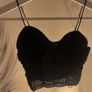 Korsett liknande topp  - En korsett liknade topp i svart från Gina Tricot. 