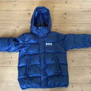 Helly Hansen  - En mörkblå Helly Hansen jacka i stl 9-10 år. Köptes till sonen men kommer inte till användning. 